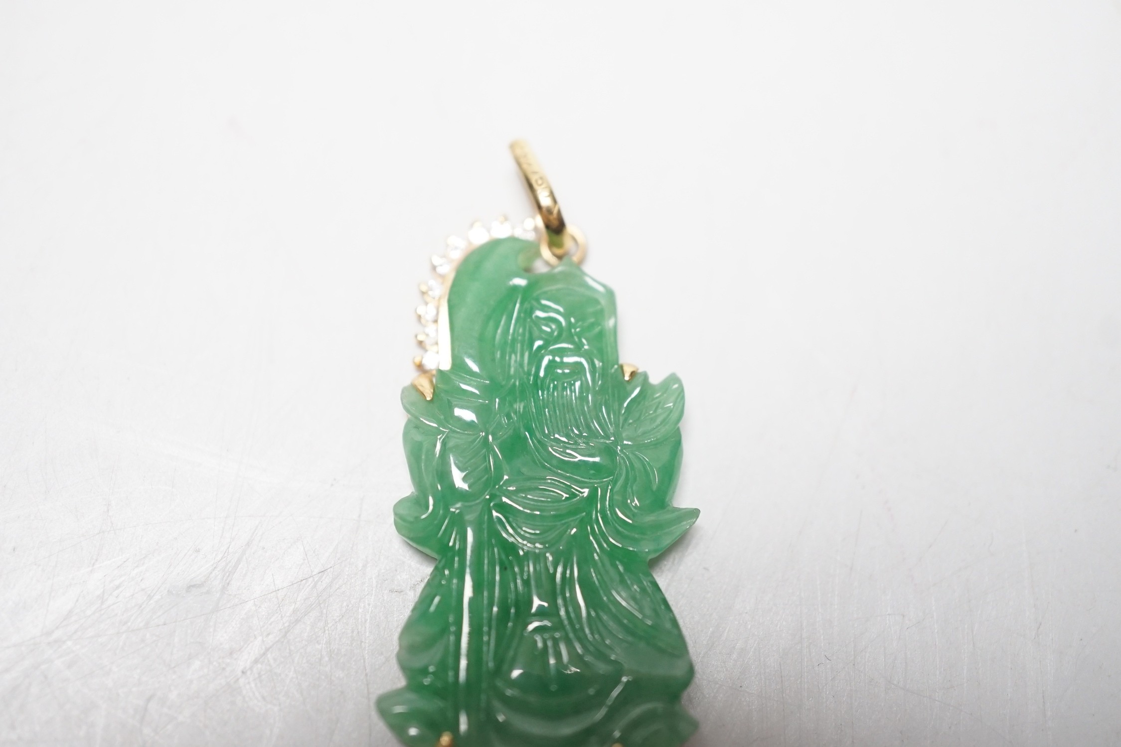 A modern 18k and diamond chip mounted jadeite pendant, carved as an immortal, 40mm, gross weight 9.1 grams.